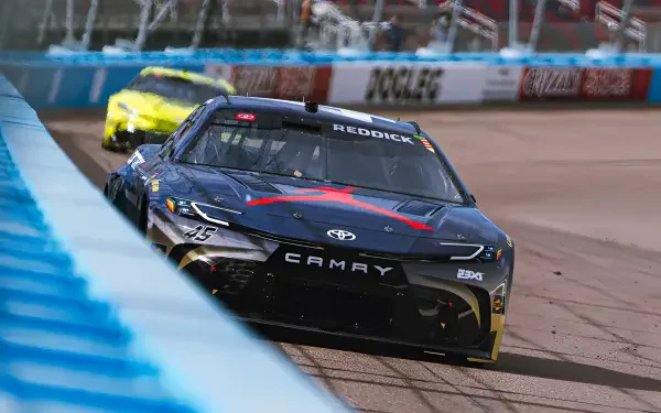 HD sports PC desktop wallpaper showing a black Toyota Camry NASCAR race car speeding on the track in a close-up action shot.