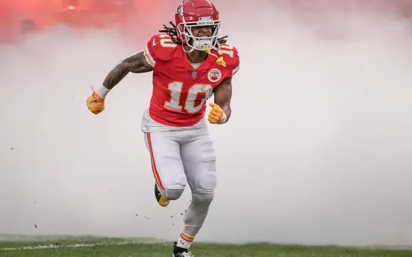 HD desktop wallpaper of a Kansas City Chiefs football player sprinting onto the field through stadium smoke in full red uniform.