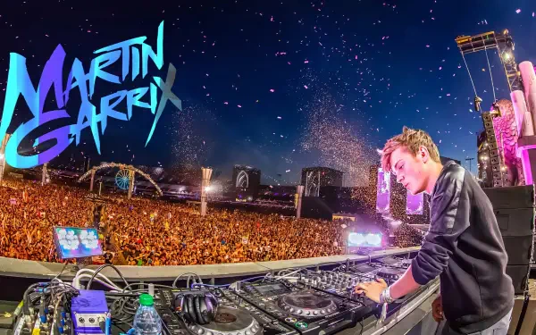 Unidentified DJ performing behind turntables at a massive music festival, vibrant lights and crowd in the night — 2K Quad HD PC desktop wallpaper/background.