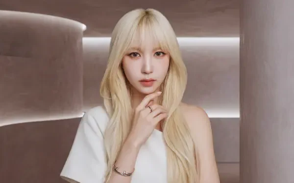 5K Ultra HD desktop wallpaper of a blonde woman with long hair in a minimalist lit room, K-pop–inspired styling, soft makeup and an elegant, poised expression against a neutral background.