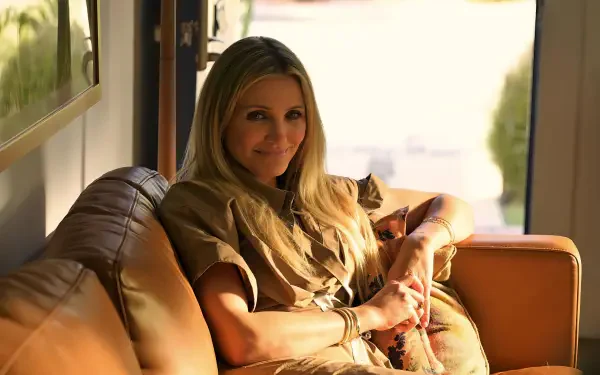 Sunlit 2K Quad HD PC desktop wallpaper: smiling actress from the movie Outcome (2026) reclining on a leather sofa in a relaxed, warm domestic scene.