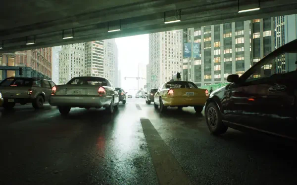 Matrix-inspired video game 4K Ultra HD PC desktop wallpaper: rain-slick city underpass with taxis and cars beneath towering skyscrapers, green-tinted cinematic lighting.