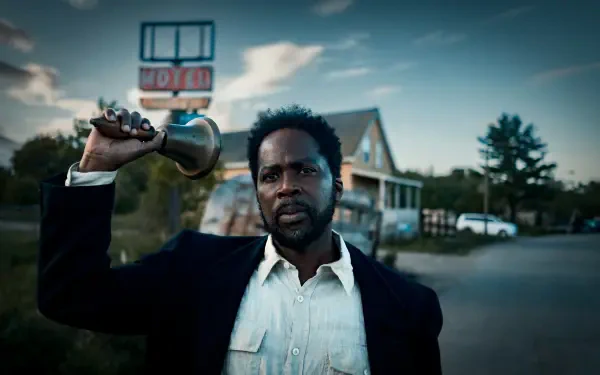 Man in a dark suit raising a handheld bell outside a roadside house at dusk — 5K Ultra HD PC desktop wallpaper from TV show From (2022).