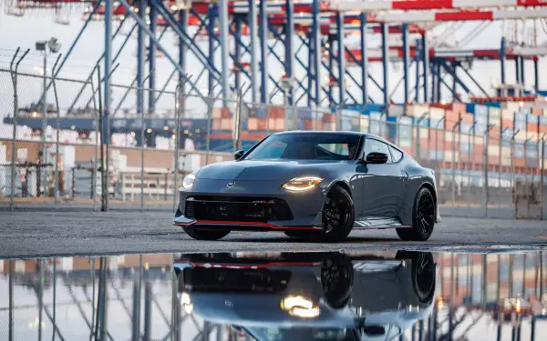 Gray Nissan Z Nismo sports car at an industrial port, reflected in wet pavement — 4K Ultra HD PC desktop wallpaper and background.