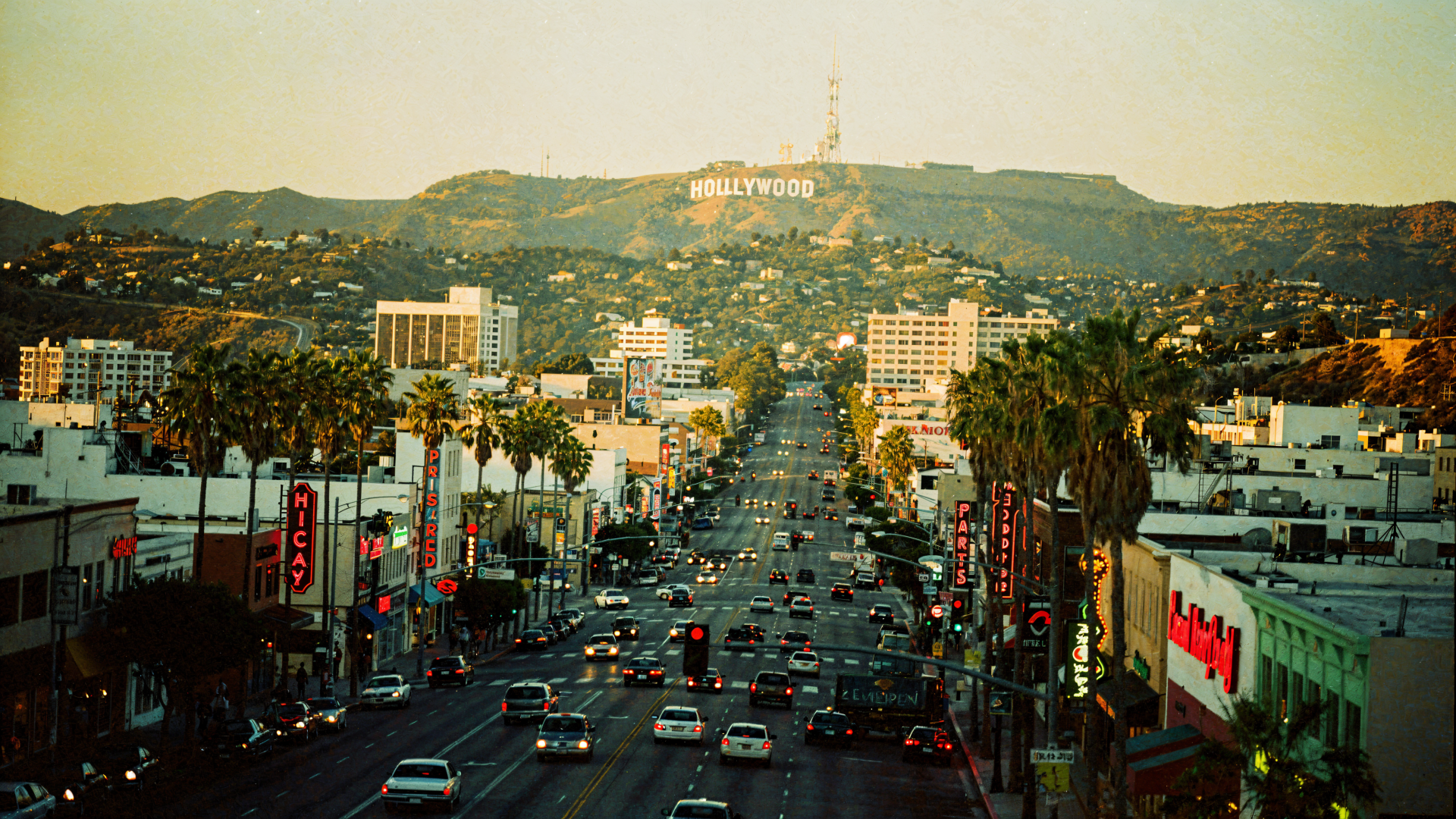4K Ultra HD PC desktop wallpaper: palm-lined city avenue at dusk leading up to the Hollywood Hills with the white Hollywood sign.