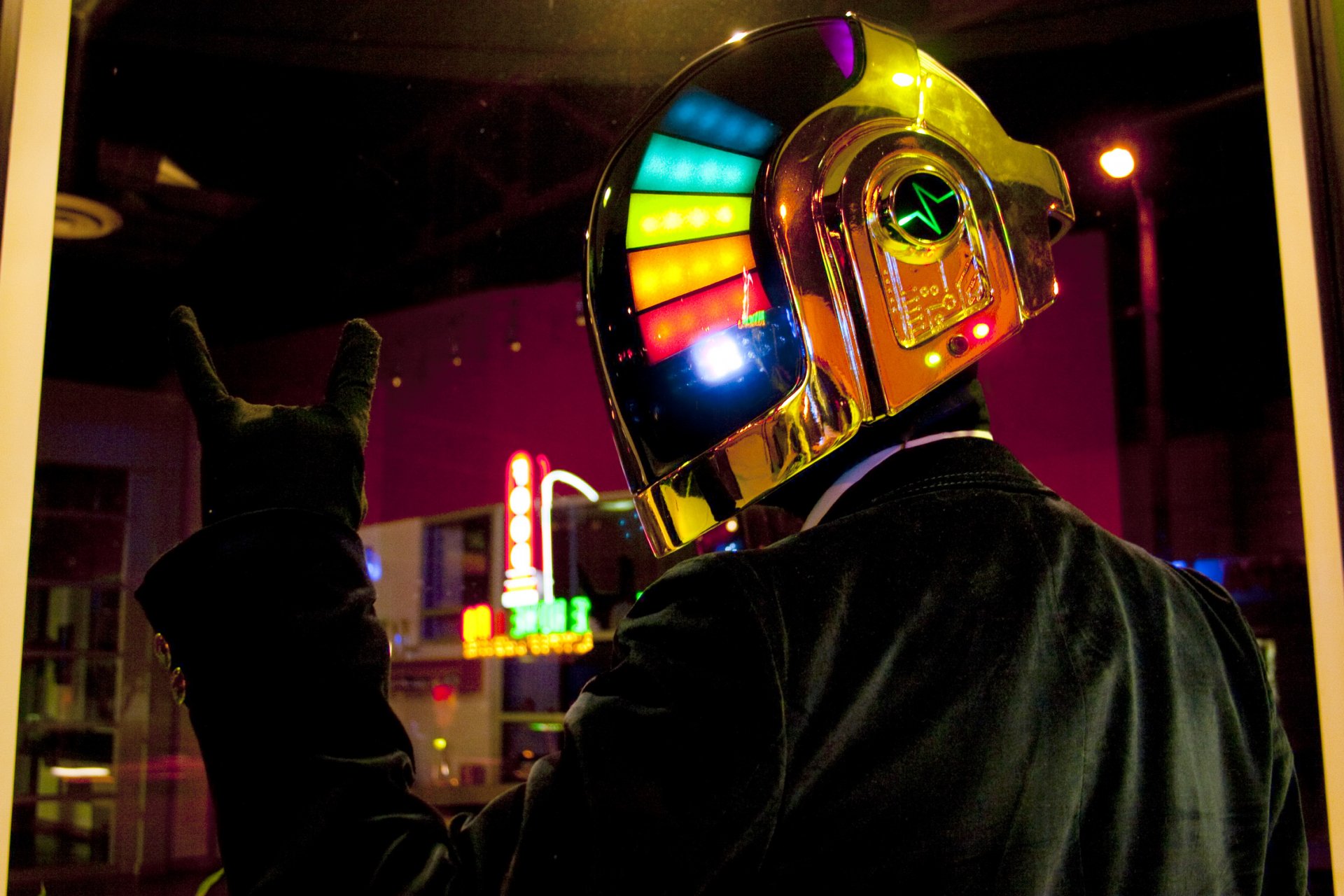 HD PC wallpaper featuring a neon-lit Daft Punk robot in a nightlife setting, with vibrant colorful lights on the helmet and a dark urban backdrop.
