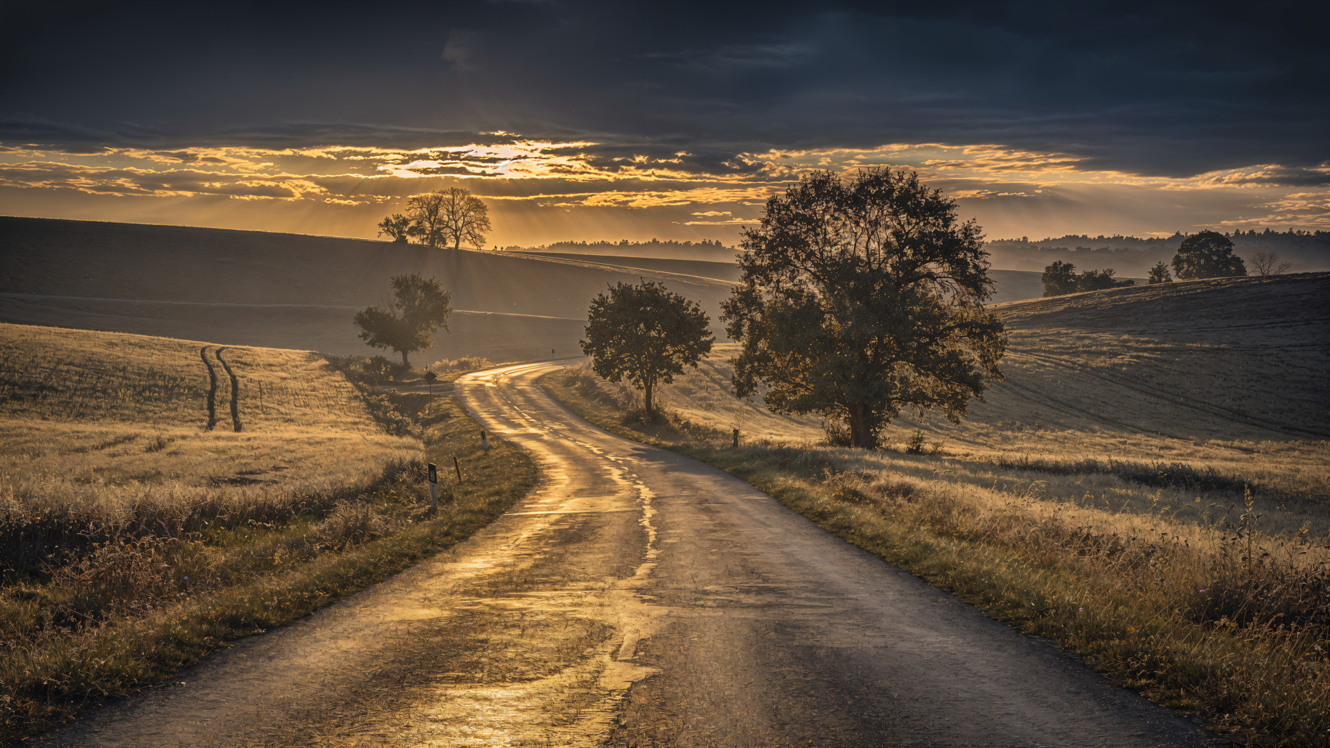 4K Ultra HD PC desktop wallpaper/background: winding country road at sunrise through rolling fields and trees beneath a dramatic sky.