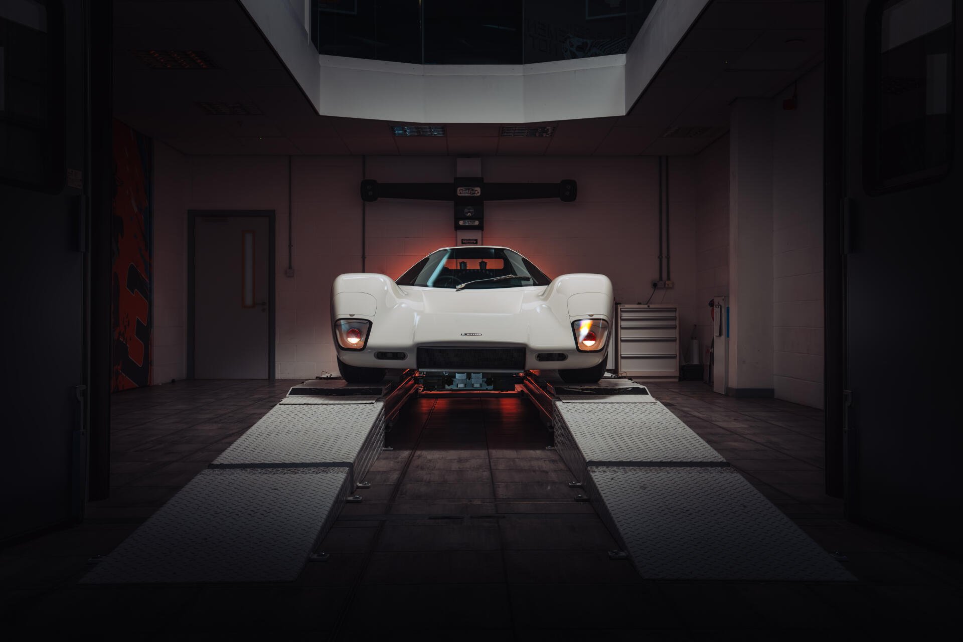 White McLaren G6GT sports vehicle front view in a dim garage, shown as an 8K Ultra HD PC desktop wallpaper/background.