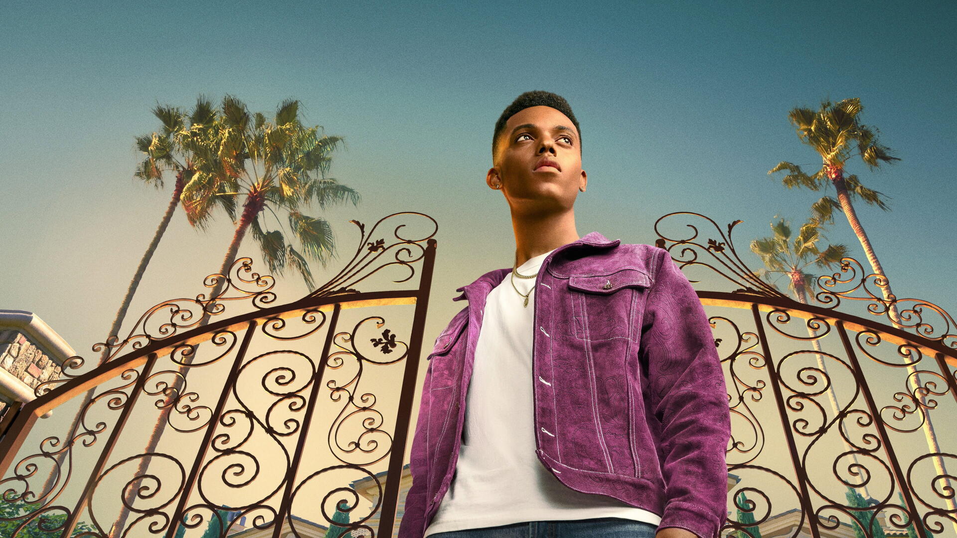 Bel-Air 4K Ultra HD PC desktop wallpaper — young man in a purple jacket stands before ornate wrought-iron gates and tall palm trees beneath a warm golden sky.