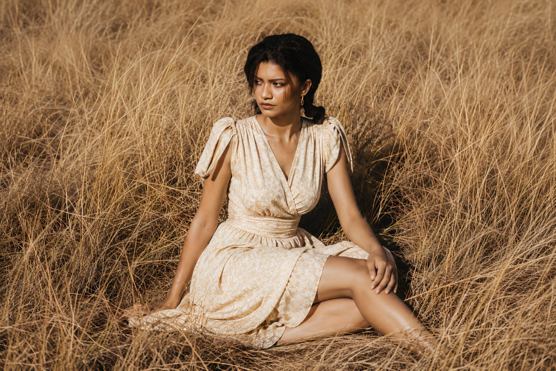 Sunlit portrait of a celebrity actress seated in tall golden grass wearing a cream dress — 4K Ultra HD PC desktop wallpaper/background.