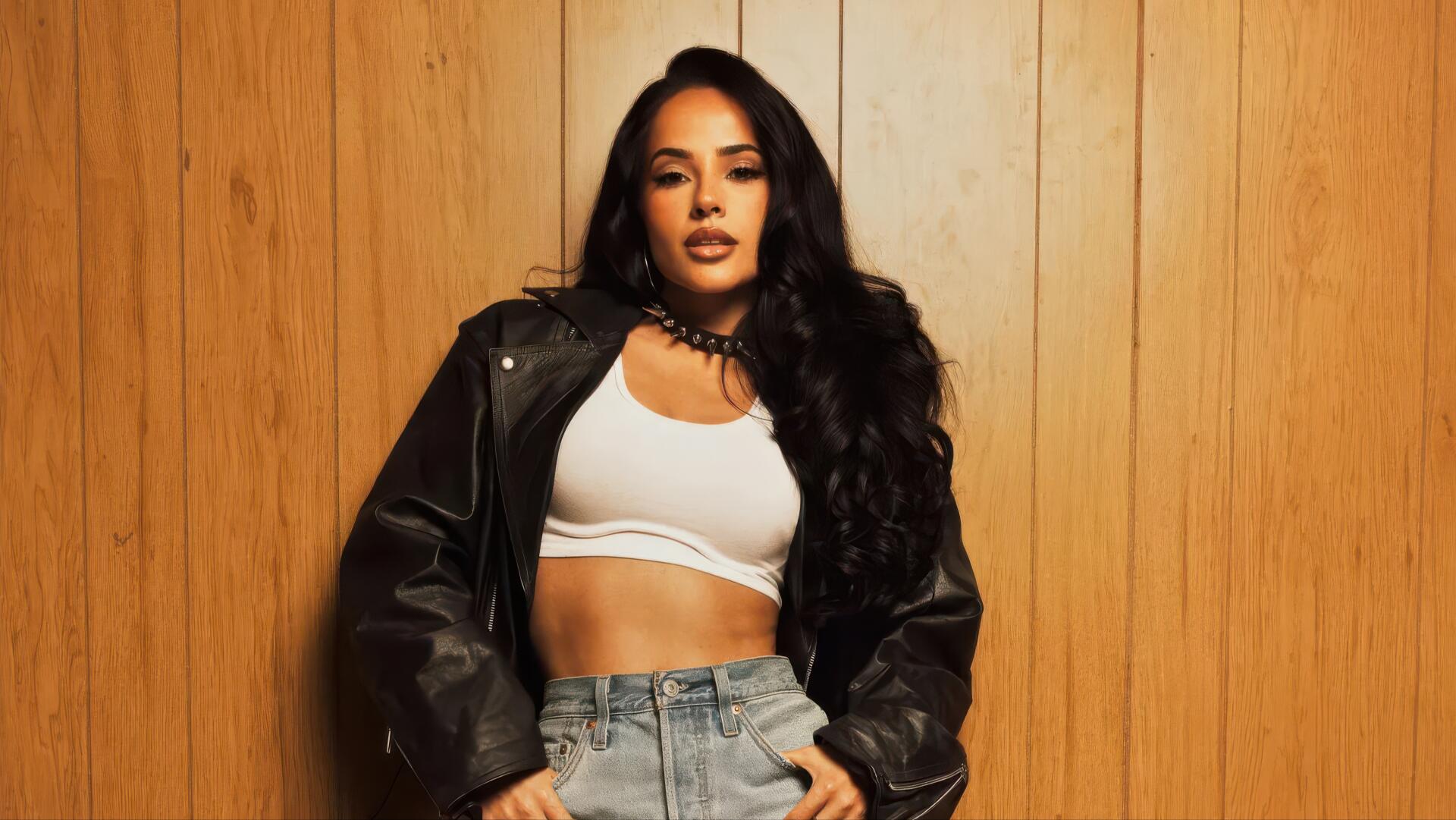 Female singer posing in a leather jacket and white crop top against wood paneling — music-themed 4K Ultra HD PC desktop wallpaper/background.