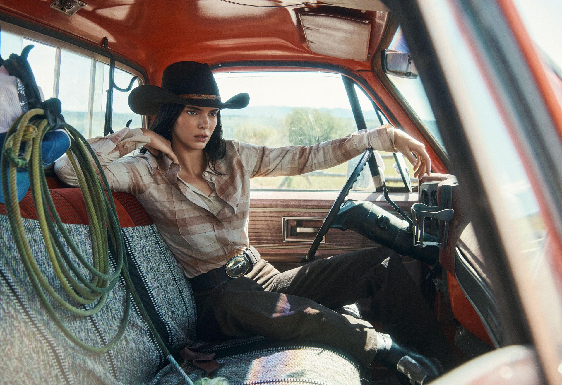 Person in a cowboy hat and plaid shirt lounging across the front seat of a vintage red pickup truck — 2K Quad HD desktop wallpaper.