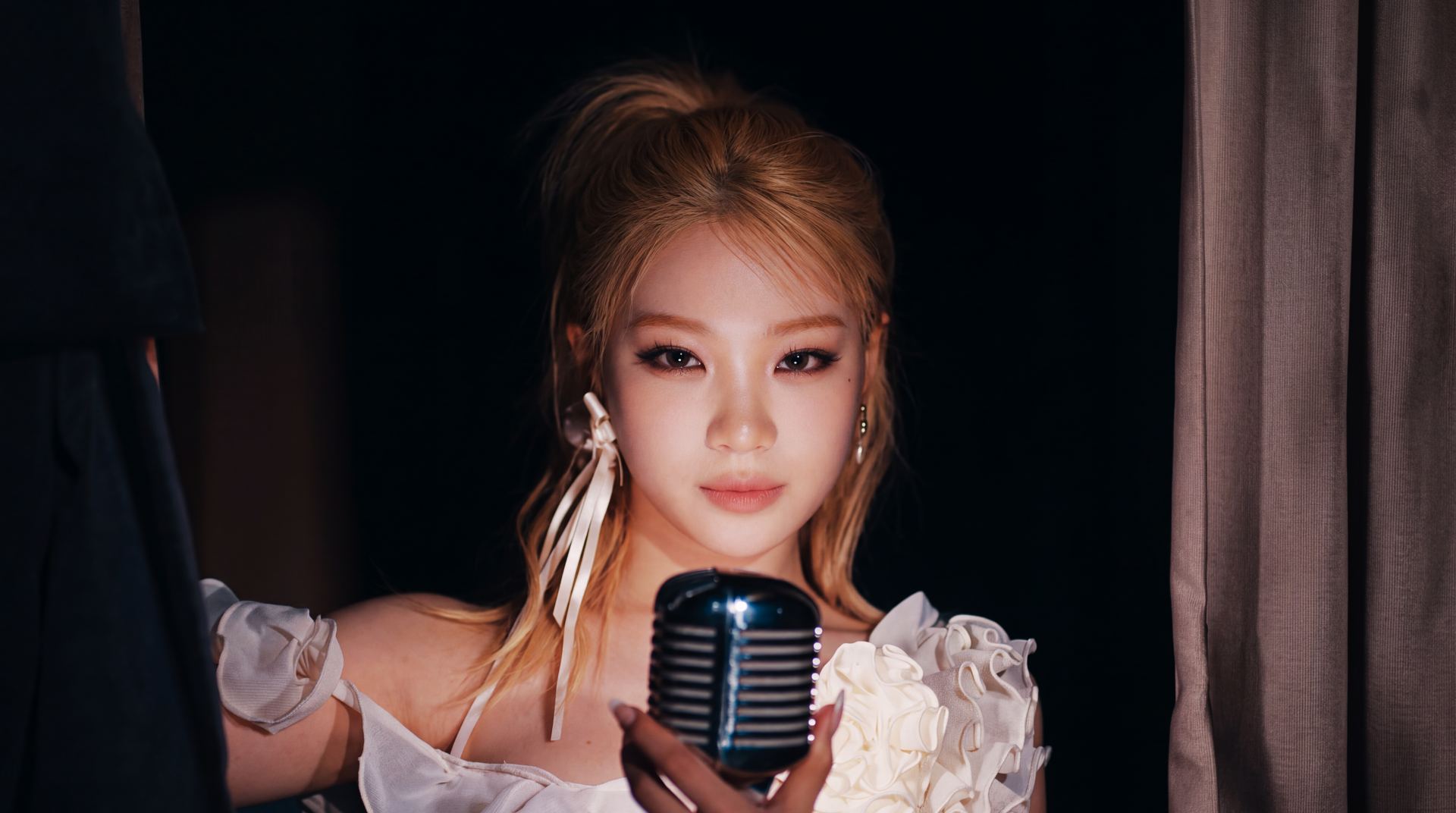 Blonde K-pop idol in a white floral stage outfit holding a vintage microphone against a dark backdrop — 5K Ultra HD PC desktop wallpaper