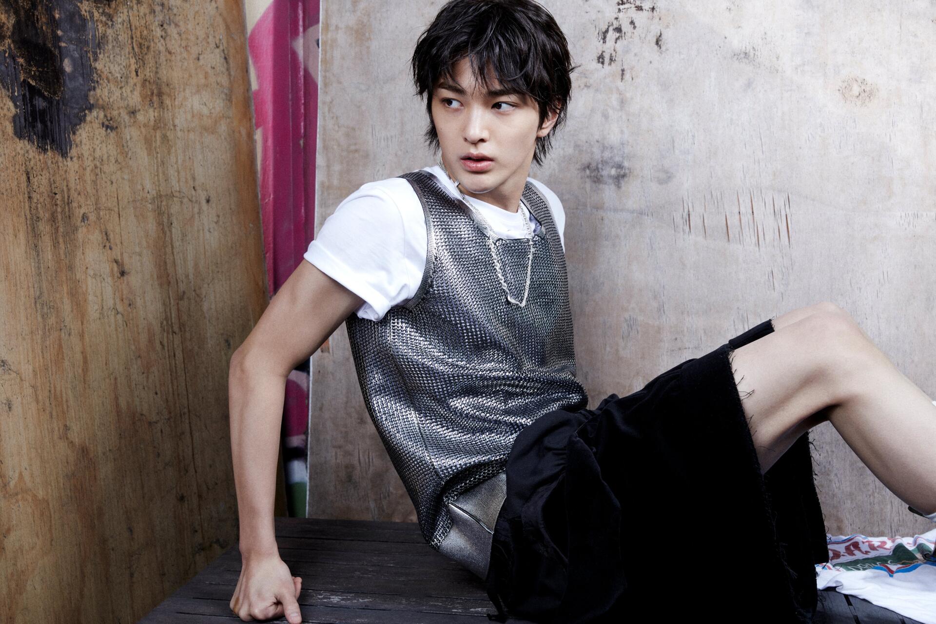 4K Ultra HD PC desktop wallpaper: 'Color Outside the Lines' portrait of a male model (tagged Cortis) seated against a distressed wall in a metallic vest and black shorts.