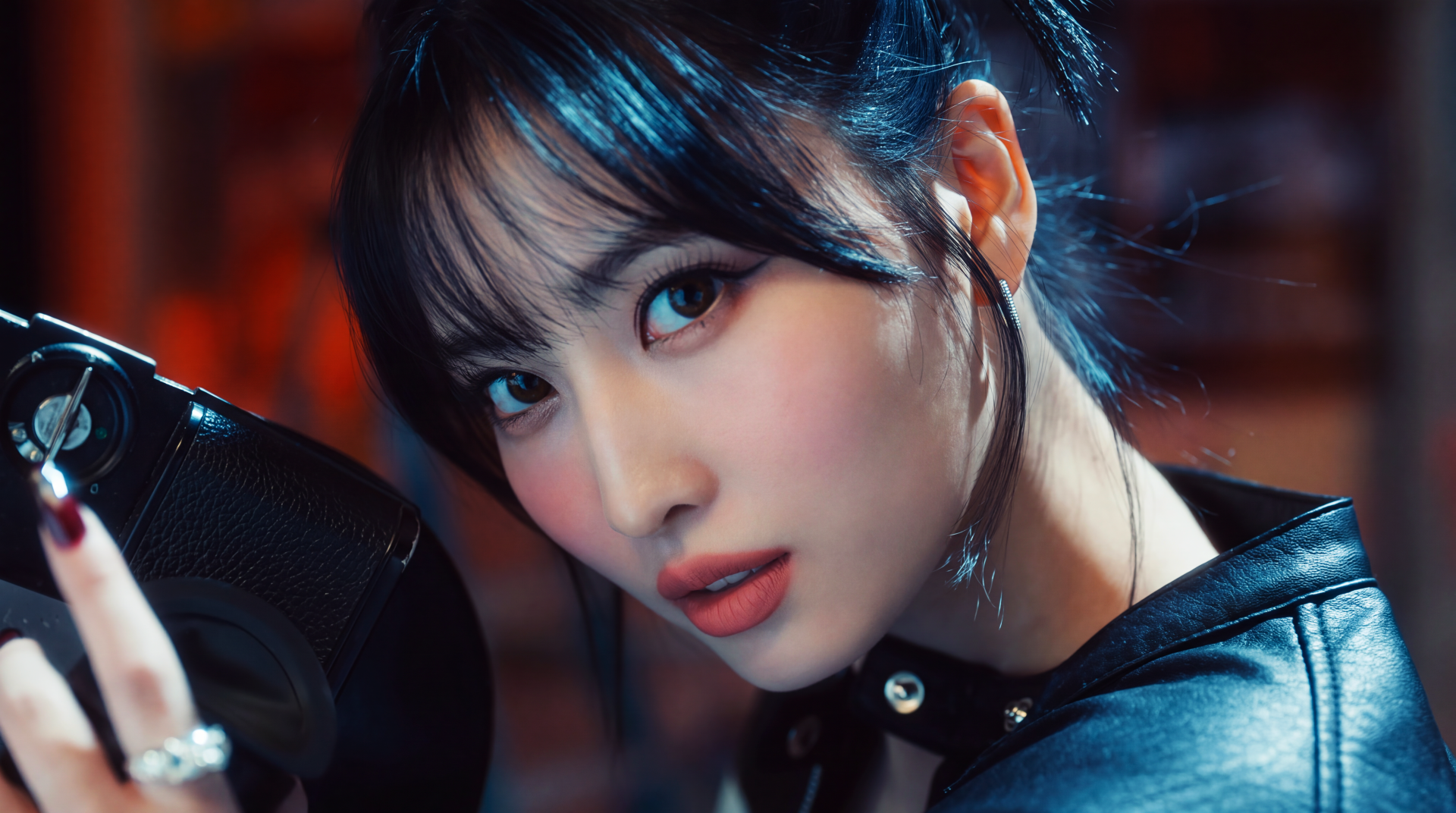 Close-up studio portrait of a young woman with dark bangs and leather jacket, dramatic makeup and dangling earring, vibrant 5K Ultra HD K-pop style desktop wallpaper.