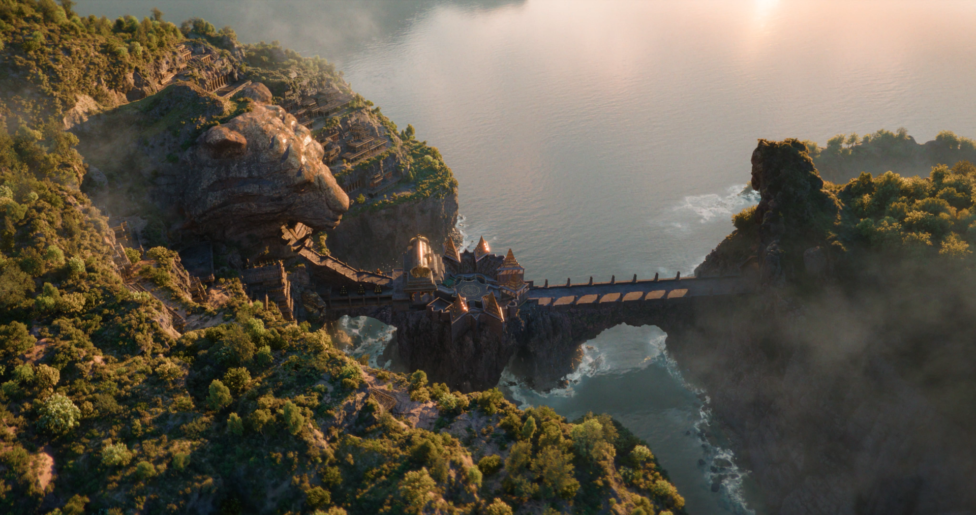 Ramayana (2026) 4K Ultra HD PC wallpaper: mist-shrouded mountains and cliffs with a stone bridge spanning a sea-swept ravine, temple-like structures perched on the cliffside.