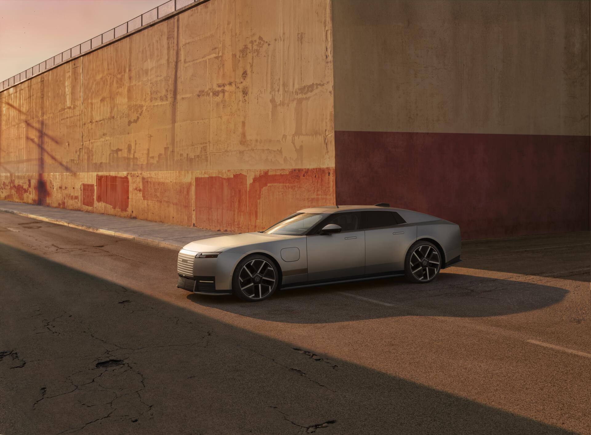 Silver Jaguar Type 01 sports car parked beside a sunlit concrete wall, featured in an 8K Ultra HD PC desktop wallpaper and background.