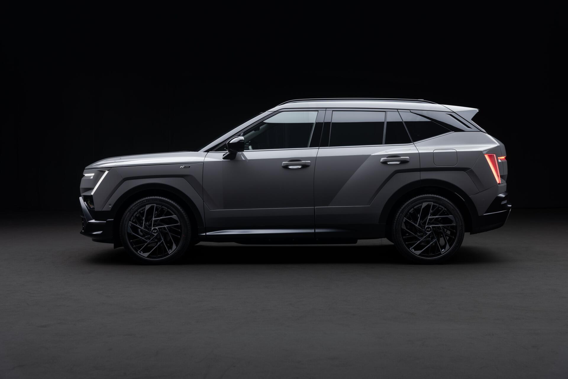 Gray Hyundai Tucson SUV in side profile against a dark studio backdrop, featured in an 8K Ultra HD PC desktop wallpaper.
