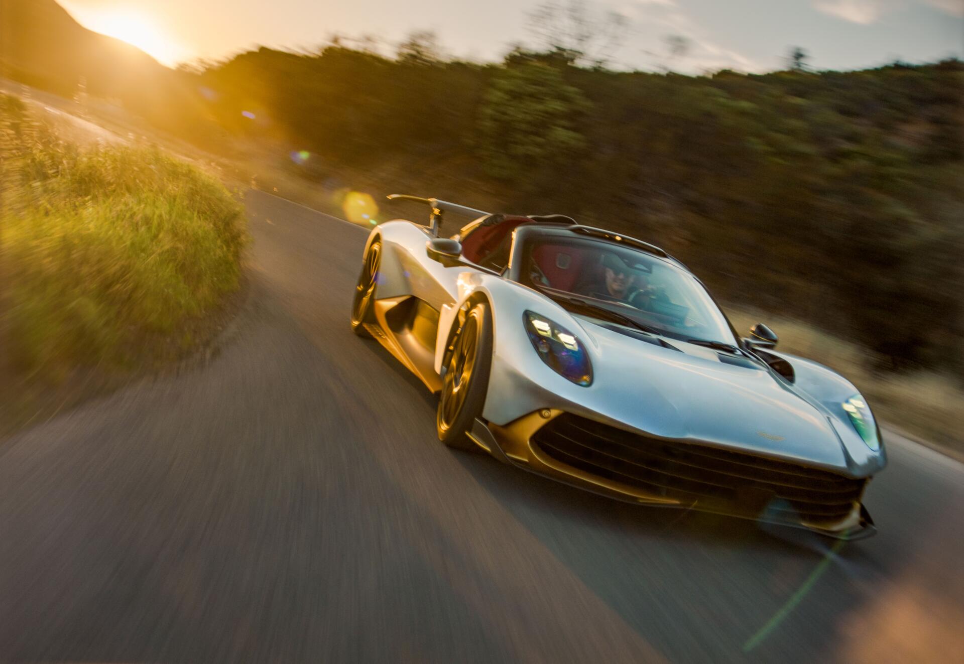 Aston Martin Valhalla Spider supercar on a forest road at golden hour, 8K Ultra HD PC desktop wallpaper and background.