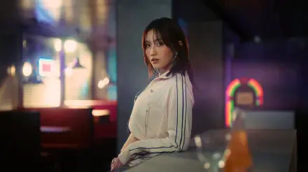 5K Ultra HD desktop wallpaper: moody neon portrait of a Japanese K-pop model in a light track jacket, TWICE/MiSaMo–inspired styling, seated at a dimly lit bar.