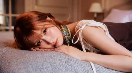 5K Ultra HD PC wallpaper — close-up of a reclining female K-pop singer/model on a bed, warm lighting and a soft, relaxed expression.