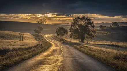 4K Ultra HD PC desktop wallpaper/background: winding country road at sunrise through rolling fields and trees beneath a dramatic sky.