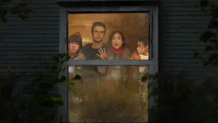 The Last House — 2K Quad HD PC desktop wallpaper showing four tense figures pressed to a fogged, cracked window, warm interior light behind a dark, weathered house exterior.