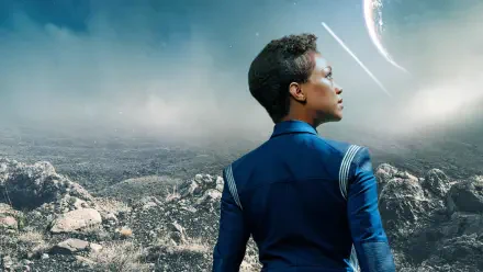 Star Trek: Discovery 2K Quad HD PC desktop wallpaper: a Starfleet officer in a blue uniform gazes across a rocky alien plain toward a distant planet.