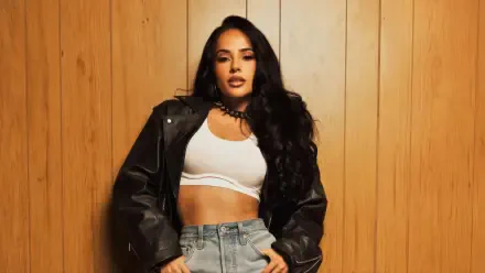 Female singer posing in a leather jacket and white crop top against wood paneling — music-themed 4K Ultra HD PC desktop wallpaper/background.