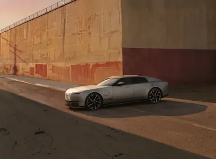 Silver Jaguar Type 01 sports car parked beside a sunlit concrete wall, featured in an 8K Ultra HD PC desktop wallpaper and background.