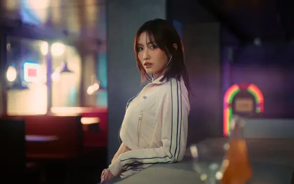 5K Ultra HD desktop wallpaper: moody neon portrait of a Japanese K-pop model in a light track jacket, TWICE/MiSaMo–inspired styling, seated at a dimly lit bar.