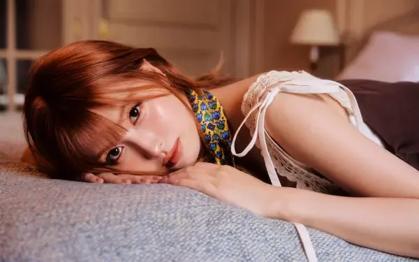 5K Ultra HD PC wallpaper — close-up of a reclining female K-pop singer/model on a bed, warm lighting and a soft, relaxed expression.