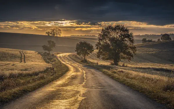 4K Ultra HD PC desktop wallpaper/background: winding country road at sunrise through rolling fields and trees beneath a dramatic sky.
