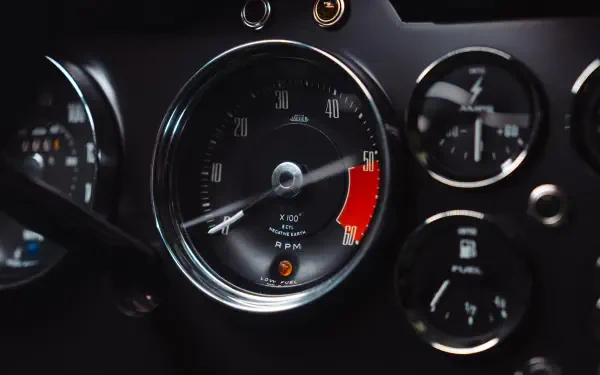 8K Ultra HD desktop wallpaper: close-up of McLaren G6GT dashboard, central tachometer and surrounding analog gauges.