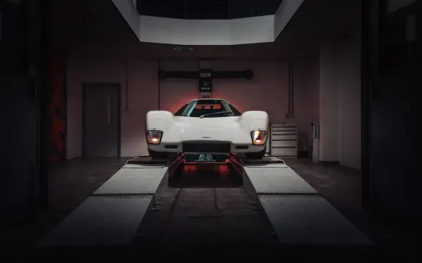 White McLaren G6GT sports vehicle front view in a dim garage, shown as an 8K Ultra HD PC desktop wallpaper/background.