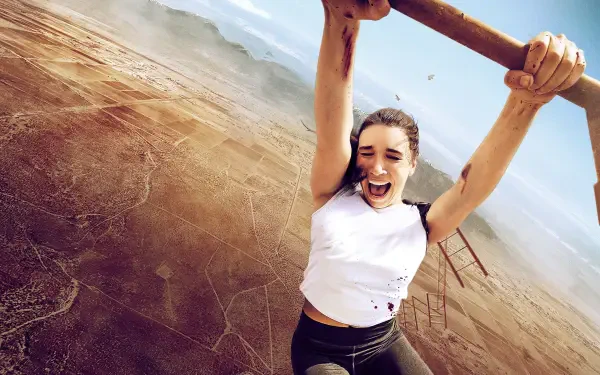 Vertigo — 4K Ultra HD PC desktop wallpaper of a woman gripping an overhead bar, dangling over a vast desert canyon with a distant bridge and wind-tousled hair.