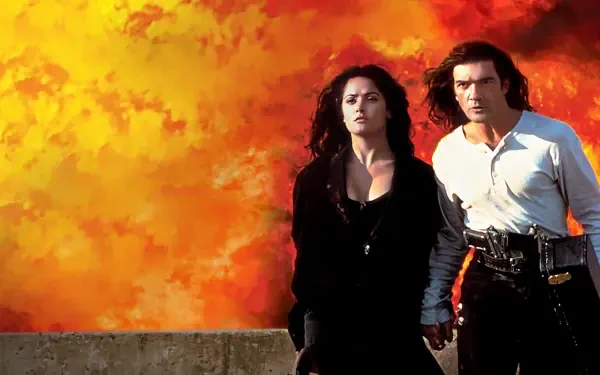 Desperado 4K Ultra HD PC desktop wallpaper and background: a man and woman hold hands on a concrete ledge as a fiery orange explosion fills the sky behind them.