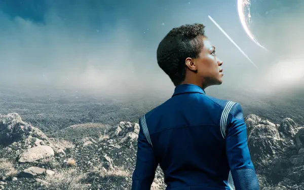 Star Trek: Discovery 2K Quad HD PC desktop wallpaper: a Starfleet officer in a blue uniform gazes across a rocky alien plain toward a distant planet.