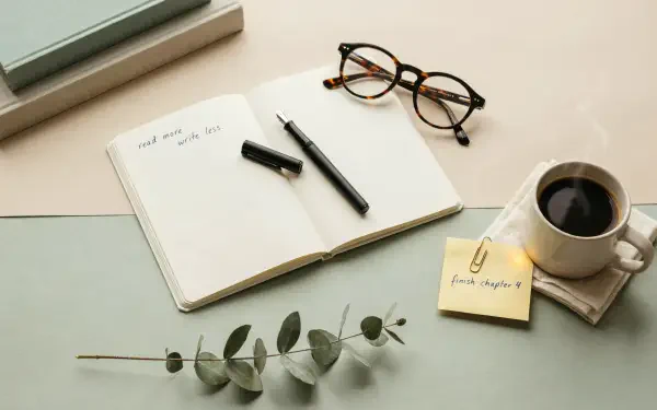 Study aesthetic 2K Quad HD PC desktop wallpaper and background: open notebook with pen, eyeglasses, coffee cup, sticky note and eucalyptus on a pale desk.