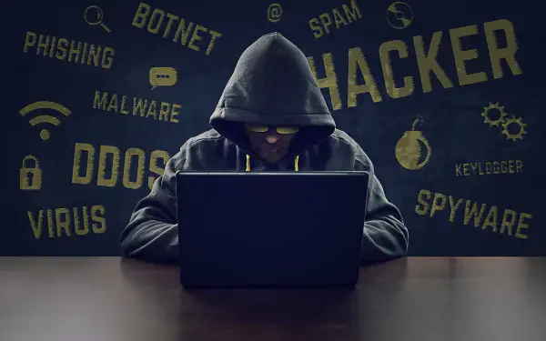 5K Ultra HD PC desktop wallpaper showing a hooded hacker at a laptop in a dark terminal-style background with words: HACKER, DDOS, MALWARE, SPYWARE.