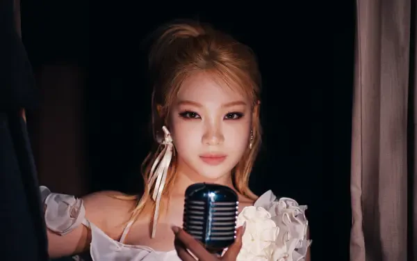 Blonde K-pop idol in a white floral stage outfit holding a vintage microphone against a dark backdrop — 5K Ultra HD PC desktop wallpaper