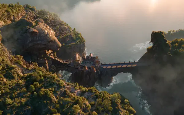 Ramayana (2026) 4K Ultra HD PC wallpaper: mist-shrouded mountains and cliffs with a stone bridge spanning a sea-swept ravine, temple-like structures perched on the cliffside.