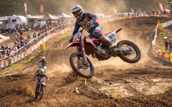 Airborne dirt bike racer on a dusty motocross track, captured in 5K Ultra HD PC desktop wallpaper and background.
