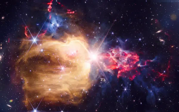 NASA James Webb Space Telescope view of NGC 7129, a glowing gold and red nebula among stars, in 5K Ultra HD desktop wallpaper.