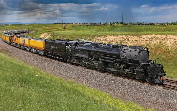 Union Pacific Big Boy 4014 steam locomotive hauling yellow Union Pacific Railroad cars through open countryside, HD desktop wallpaper background.