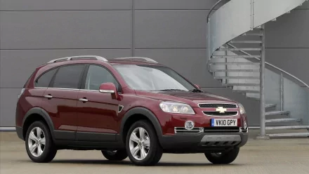 Maroon Chevrolet Captiva vehicle parked beside a modern concrete building with a spiral staircase, HD PC desktop wallpaper/background.