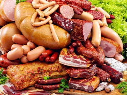 HD desktop wallpaper showcasing a rich assortment of meats including sausages, cured cuts, and bacon, arranged with fresh greens for a vibrant food-themed background.