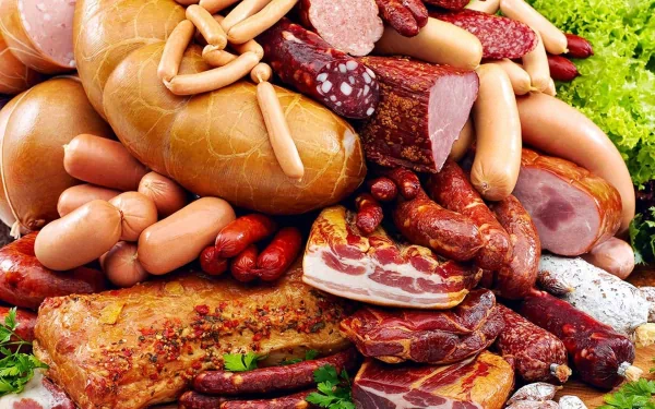 HD desktop wallpaper showcasing a rich assortment of meats including sausages, cured cuts, and bacon, arranged with fresh greens for a vibrant food-themed background.