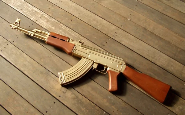 HD desktop wallpaper featuring a man-made AKM assault rifle with wooden accents resting on a wooden floor.