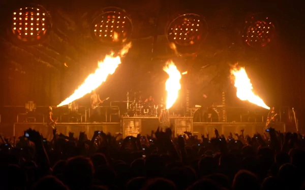 HD PC desktop wallpaper capturing Rammstein's fiery live music performance with intense flames lighting up the stage and an energetic crowd.